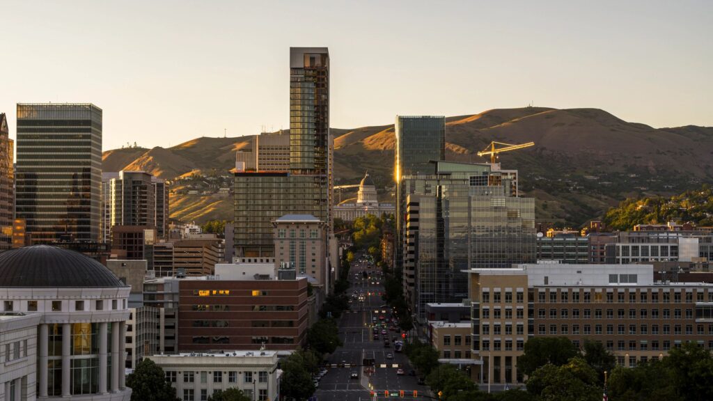 Sunset illuminates high-rise buildings. State Street stretches through Liberty-Wells district of Salt Lake City, Utah leading to State Capitol.